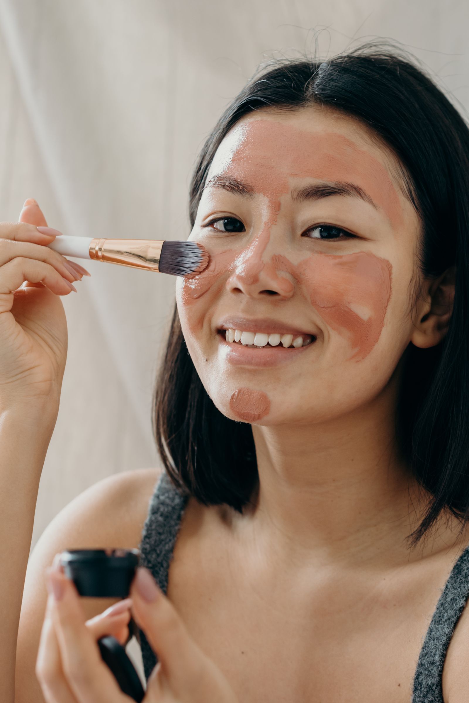Smiling Asian woman with clay mask, acne care Dubai